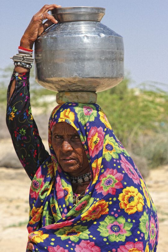 Mujer cargando un recipiente de agua en la cabeza en Bikaner